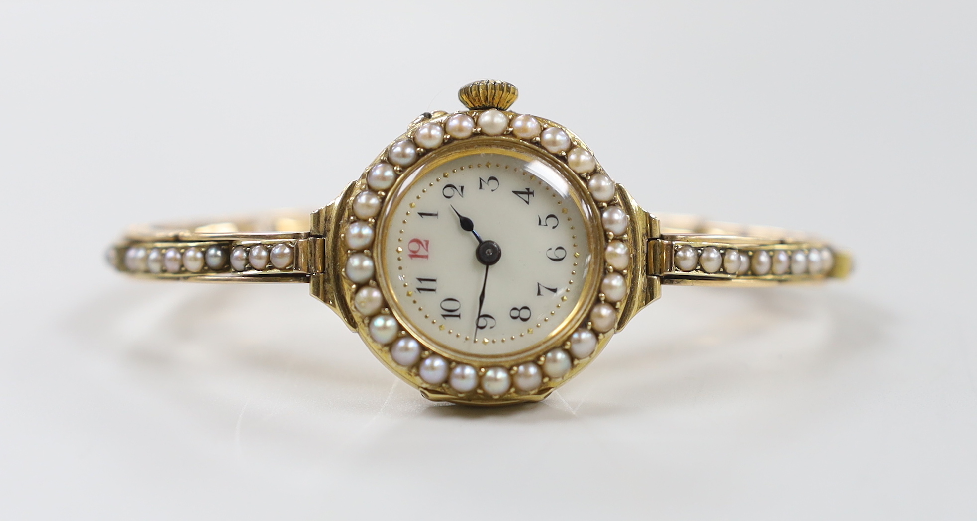 A lady's early 20th century 18ct gold and seed pearl set manual wind wrist watch, on a flexible 15ct and seed pearl set bracelet